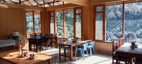 una sala da pranzo con tavoli, sedie e finestre di Hotel Apple Flower, by Manali Mall Road Resorts, Near Hadimba Temple a Manāli