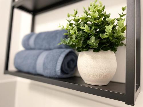 a white vase with a plant on a shelf with towels at Zentrales Innenstadt Studio mit Garage in Stuttgart