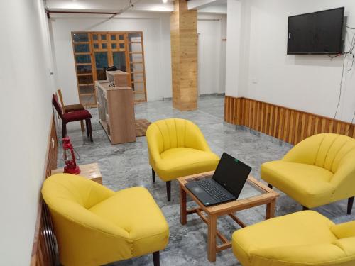 a room with yellow chairs and a laptop on a table at Hotel Apple Flower in Manāli