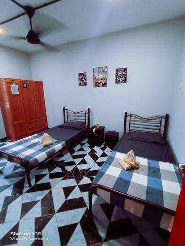 two beds in a room with a checkered floor at Homestay D'Lapang near KLIA in Sepang