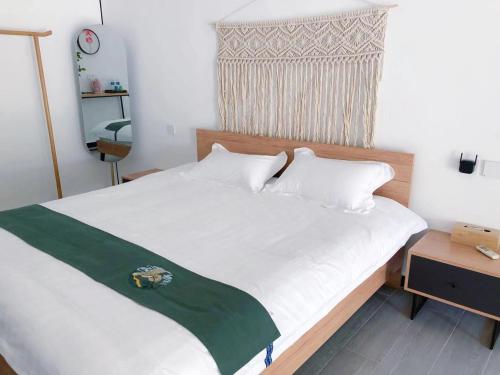 a bed with white sheets and a green blanket on it at 隐谷私院The Great Wall Valley in Gubeikou