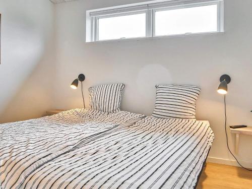 a bedroom with a bed with two lamps and a window at Holiday home Nexø IX in Neksø