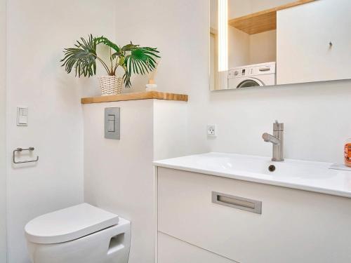 a white bathroom with a toilet and a sink at Holiday home Nexø IX in Neksø