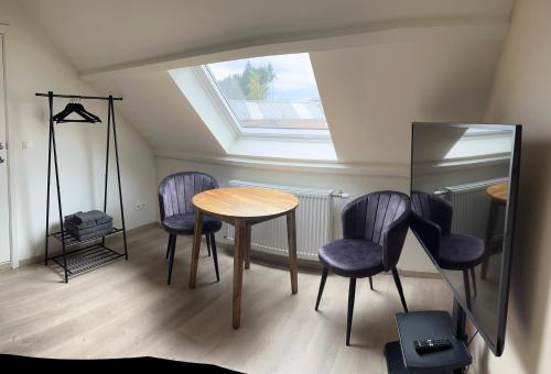 a table and chairs in a room with a skylight at Ecole Buissonnière in Vielsalm