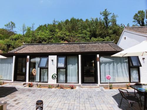a building with windows and a patio with a table at 隐谷私院The Great Wall Valley in Gubeikou