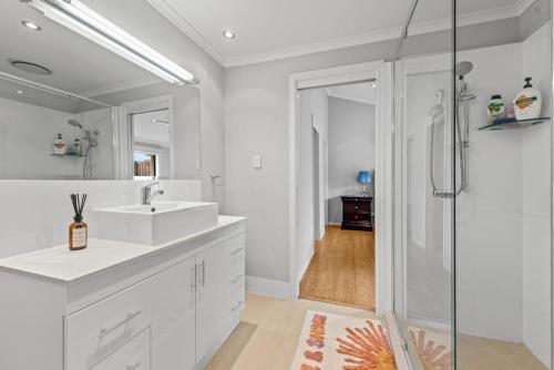 a white bathroom with a sink and a shower at Serene Lakefront Villa with Private Pool 