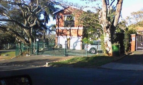 a house with a green fence in front of a house at The Treehouse in Amanzimtoti