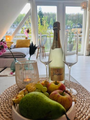 a table with a bottle of champagne and a basket of fruit at Moderner Altbau mit Infrarotsauna im Grünen in Witten