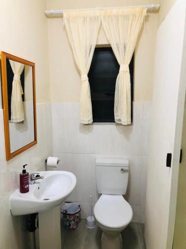 a bathroom with a toilet and a sink and a window at Peshline Guest House Unit 3 in Ermelo