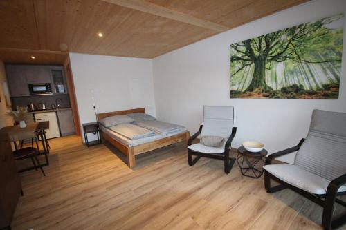a bedroom with a bed and chairs and a painting on the wall at Raichberg Appartements in Hechingen