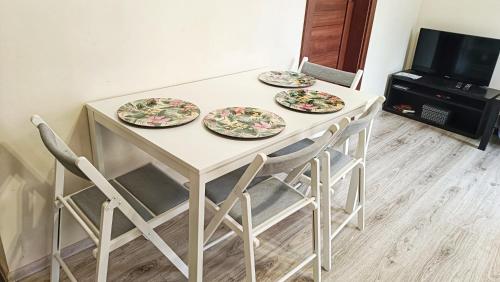 a table with four plates on it with chairs at Apartament Jola in Polanica-Zdrój