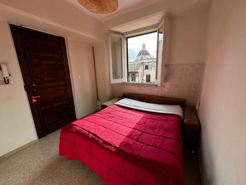 una camera con letto rosso e finestra di Casa in centro a Foligno