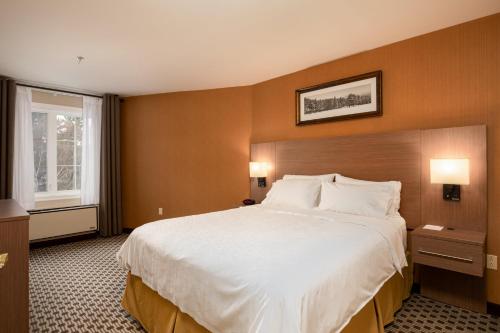 a hotel room with a large bed and a window at Holiday Inn Express & Suites Tremblant by IHG in Mont-Tremblant