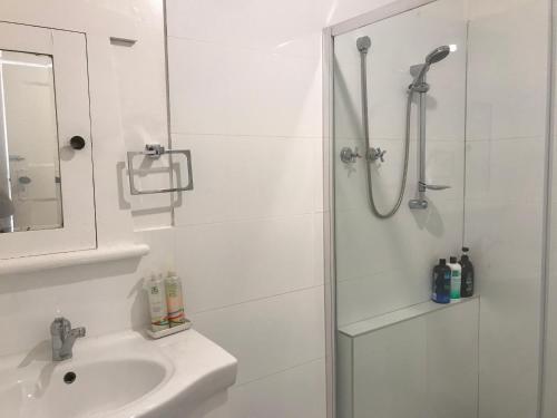 a white bathroom with a shower and a sink at D114 Victorian Central Stay in Melbourne