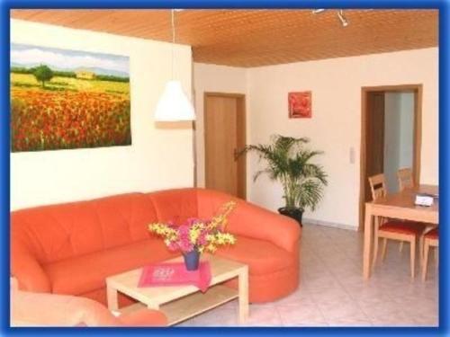 多因的住宿－Ferienwohnung für 6 Personen ca 68 qm in Daun-Weiersbach, Rheinland-Pfalz Moseleifel，客厅配有橙色沙发和桌子