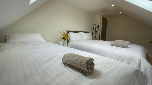1 dormitorio con 2 camas con sábanas blancas en Spire attic apartment no kitchen, en Dublín