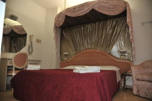 a bedroom with a large red bed with a canopy at Hotel Baia Marina in Cattolica
