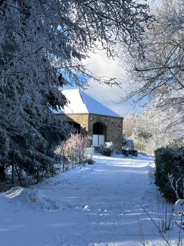 a barn in a snow covered yard with trees at Ecole Buissonnière in Vielsalm