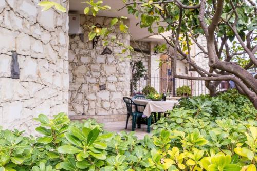 un patio con tavolo e sedie accanto a un muro di pietra di Ferienwohnung für 2 Personen 2 Kinder ca 50 qm in Taormina, Sizilien Ostküste von Sizilien a Taormina