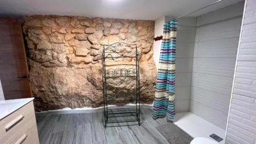 y baño con pared de piedra y ducha. en Casa Cueva Toni, en Alcalá del Júcar