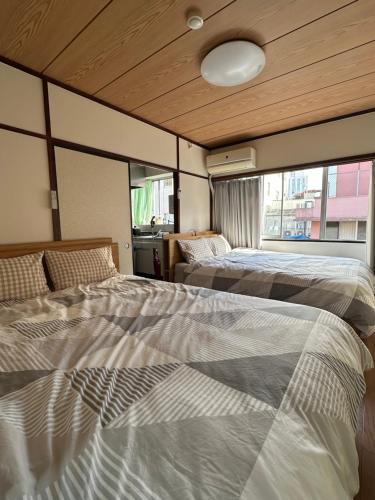 two beds in a room with windows at ｊR蒲田駅1分空港近い in Tokyo