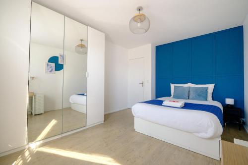 Schlafzimmer mit einem blauen und weißen Bett und einem Spiegel in der Unterkunft La Rouette - Chambres privées in Reims