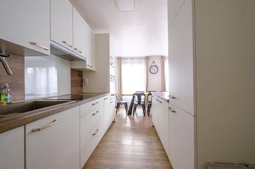 une cuisine avec des armoires blanches et un plancher en bois dans l'établissement La Rouette - Chambres privées, à Reims