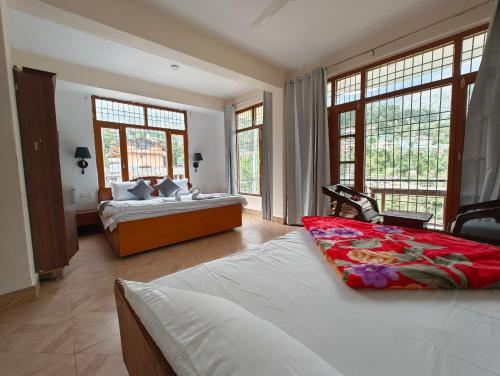 a bedroom with two beds and large windows at Vibes by Vicctoria House in McLeod Ganj