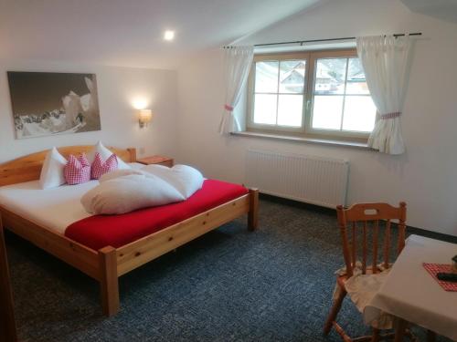 a bedroom with a bed and a window and a chair at Landhaus Alpenjäger in Sölden