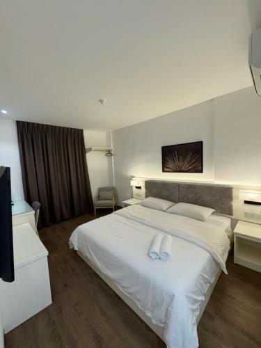 um quarto com uma cama branca com duas toalhas em 52 The Grace hotel em Muar