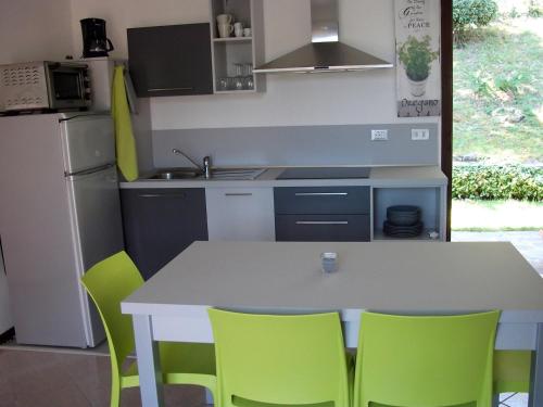 uma cozinha com uma mesa branca e cadeiras verdes em Ferienwohnung für 4 Personen ca 45 qm in Piovere, Gardasee Westufer Gardasee em Piovere