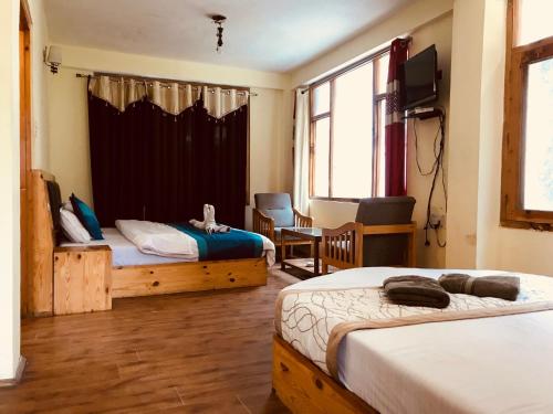 a bedroom with two beds and a tv in it at DevDham Lodge in Chandīgarh
