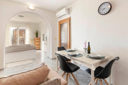 - un salon avec une table, des chaises et une horloge dans l'établissement Apartment Martin, à Koper