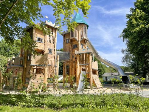 a playground with a slide in front of a building at Camping Fuussekaul in Heiderscheid