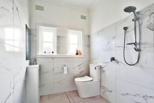 a white bathroom with a toilet and a shower at Charming 3 Bedroom on the edge of Downtown Herford St 2 E-Bikes Included in Sydney