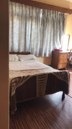 a bed in a bedroom with a window and a dresser at Hotel Lumbini Resort in Pokhara