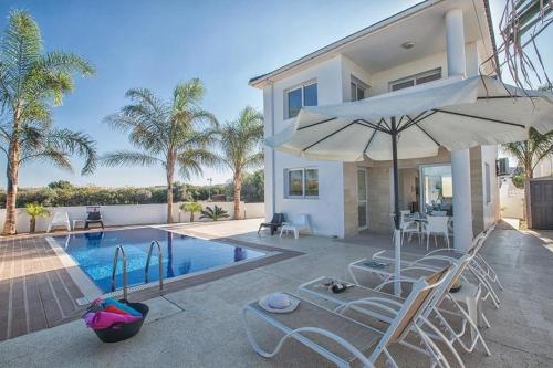 a villa with a swimming pool with chairs and an umbrella at Ferienhaus mit Privatpool für 6 Personen ca 130 qm in Pernera, Südküste von Zypern - b59089 in Protaras