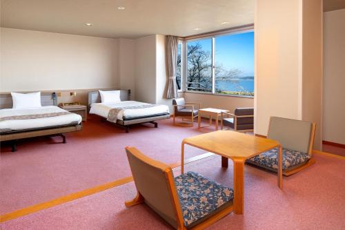 a hotel room with two beds and a table and chairs at KAMENOI HOTEL Itako in Itako