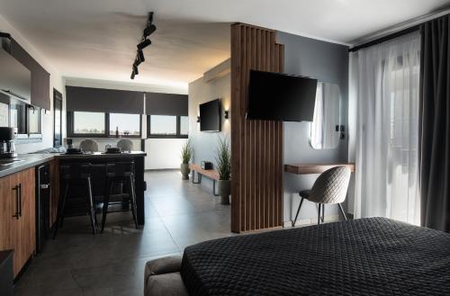 a bedroom with a bed and a kitchen with a desk at StayInn Luxury Apartments in Nea Kalikratia