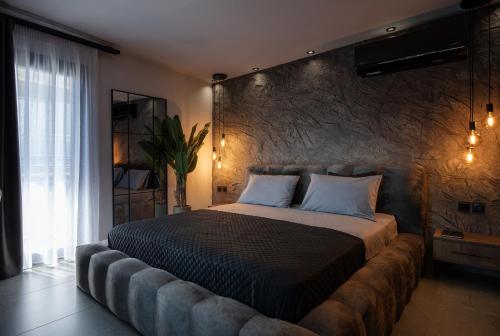 a bedroom with a large bed with a stone wall at StayInn Luxury Apartments in Nea Kalikratia