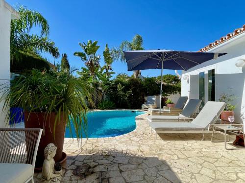 una piscina con sillas y una sombrilla junto a una casa en VILLA OASIS SEA VIEW 3 bed PRIVATE HEATED POOL - La Cala de Mijas by Solrentspain en Mijas Costa