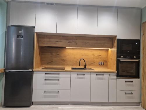 a kitchen with white cabinets and a stainless steel refrigerator at Apartament K&H W Centrum in Tarnów