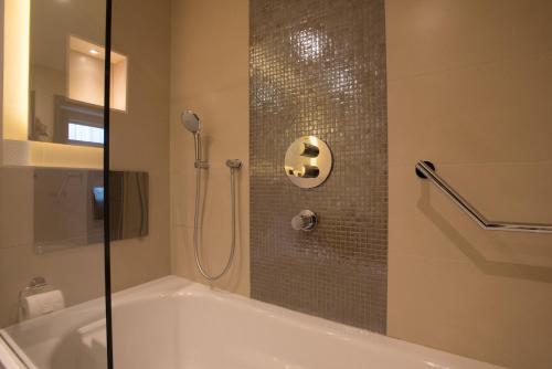 a bathroom with a tub and a shower with a glass door at St George's Hotel - Wembley in London
