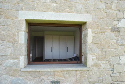 a window in a stone wall with a closet at Casa los Canarios in Irijoa