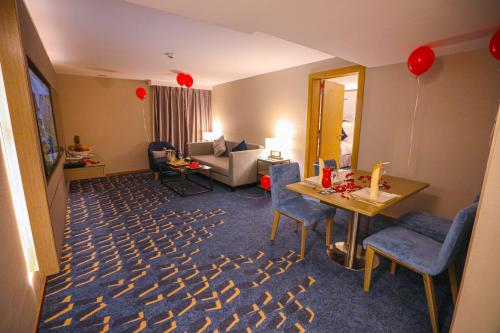 Cheerful Al Waha Hotel Unayzah - فندق شيرفل عنيزة في عنيزة: غرفة مع غرفة معيشة مع طاولة وكراسي