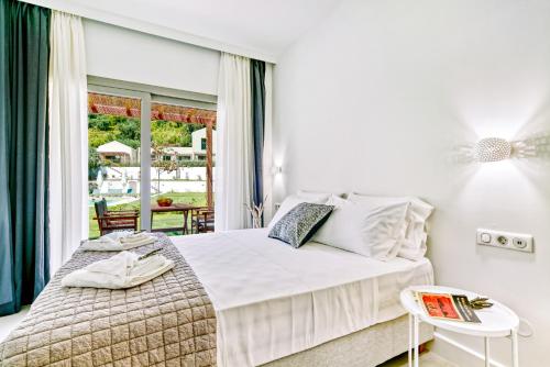 a white bedroom with a bed and a table at Kumquart estate- Bergamot in Aspiotádes