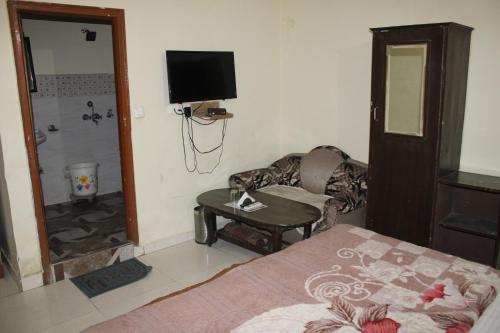 een slaapkamer met een bed, een bank en een televisie bij MID CITY HOTEL & RESTO in Chandīgarh