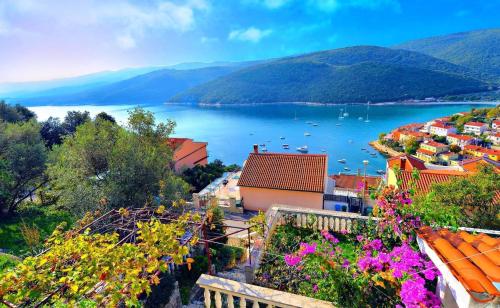 een uitzicht op een stad op het water met bloemen bij Ferienwohnung für 2 Personen ca 30 qm in Rabac, Istrien Bucht von Rabac in Rabac