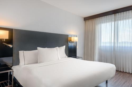 un grande letto bianco in una camera d'albergo di AC Hotel Vicenza by Marriott a Vicenza