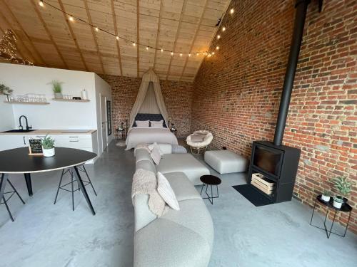 a room with a brick wall and a bed and a tv at Boven de paarden @ de Hoeveschuur in Riemst